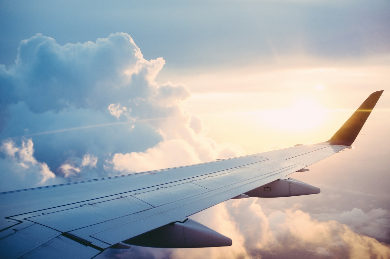 Traveler wearing over-ear headphones by an airplane window.