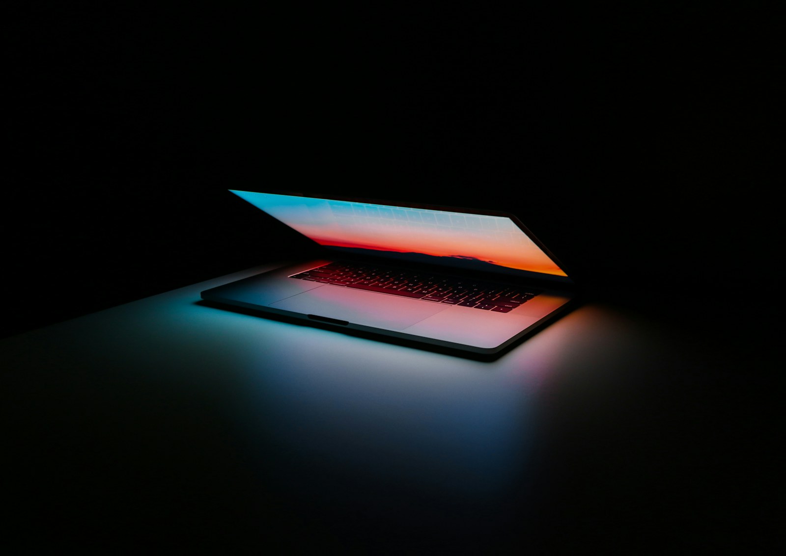 Portable SSD connected to a laptop beside a camera and memory cards.